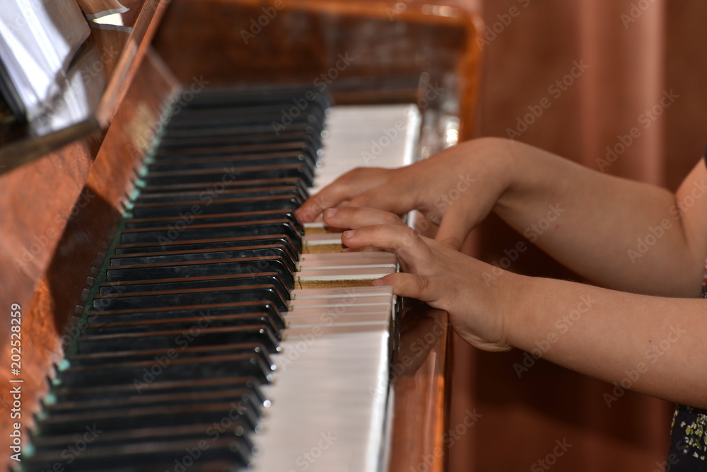 The boy plays the brown piano on notes.