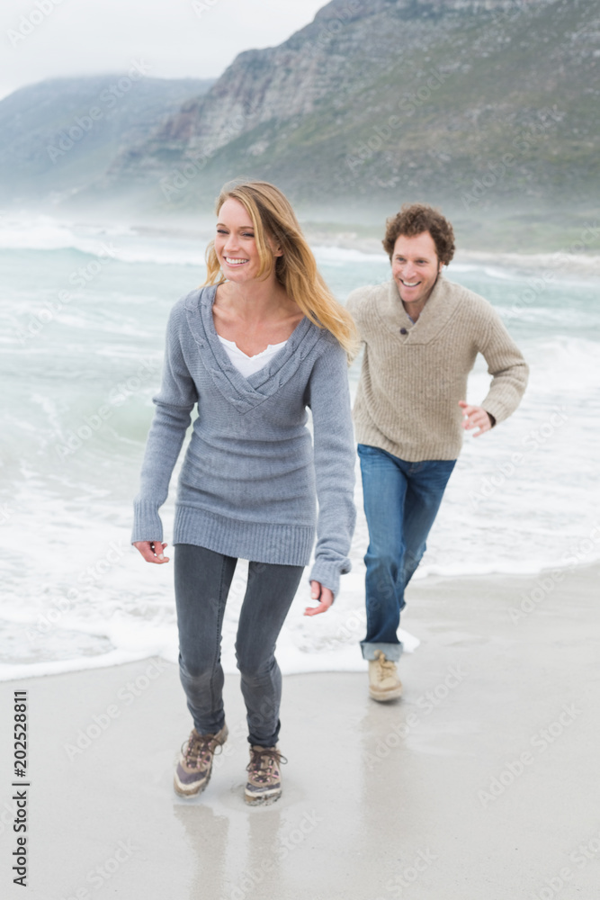 Happy casual young couple running at beach