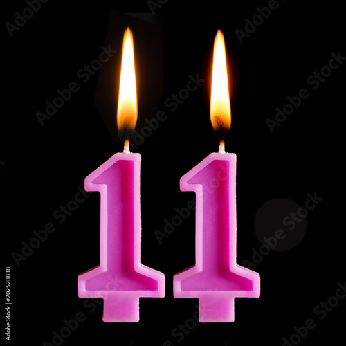 Burning birthday candles in the form of 11 eleven figures for cake isolated on black background. photo