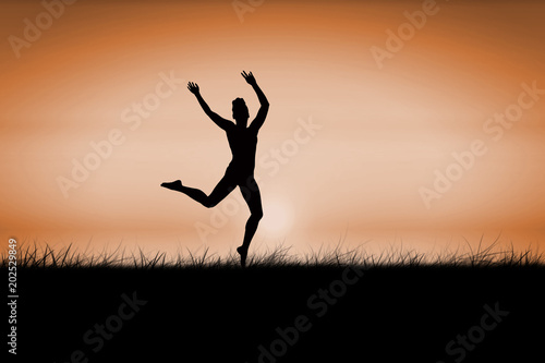 Fit brunette jumping and posing against sunrise