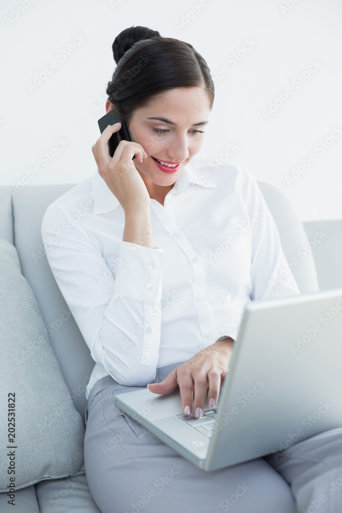 Well dressed woman using laptop and cellphone on sofa Well dressed woman using laptop and cellphone on sofa