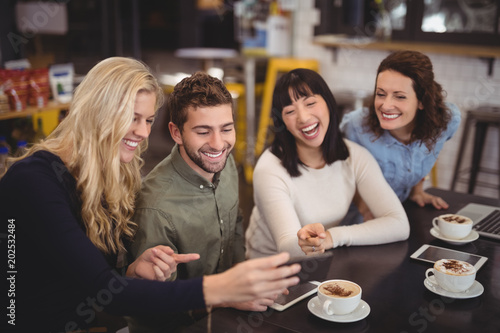 Cheerful friends using digital tablet while sitting at coffee shop