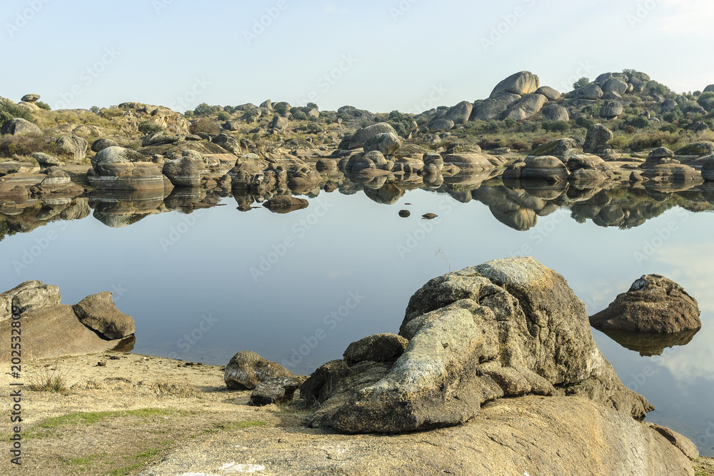 scenery with reflexes in the water of the park and natural monument of the Barruecos in Malpartida of Caceres in Caceres, Extremadura, Spain, 