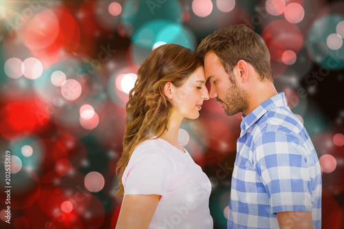 Young couple rubbing nose against digitally generated twinkling light design 