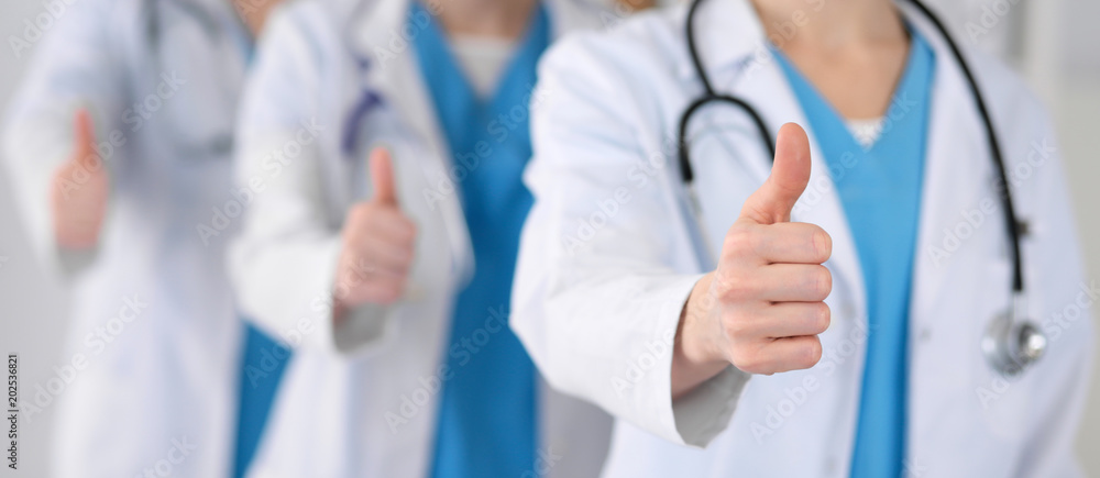 Groupe of medicine doctors show OK sign with thumb up close up. Success and high level service in health care, best treatment and customer loyalty and physical concept. Copy space for advertisement Groupe of medicine doctors show OK sign with thumb up close up. Success and high level service in health care, best treatment and customer loyalty and physical concept. Copy space for advertisement