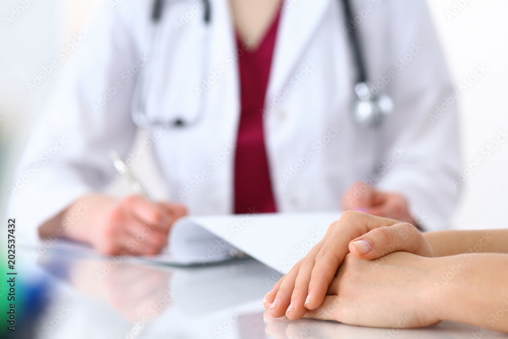 Female doctor filling up an application form while consulting patient. Just hands. Medicine and health care concept Female doctor filling up an application form while consulting patient. Just hands. Medicine and health care concept