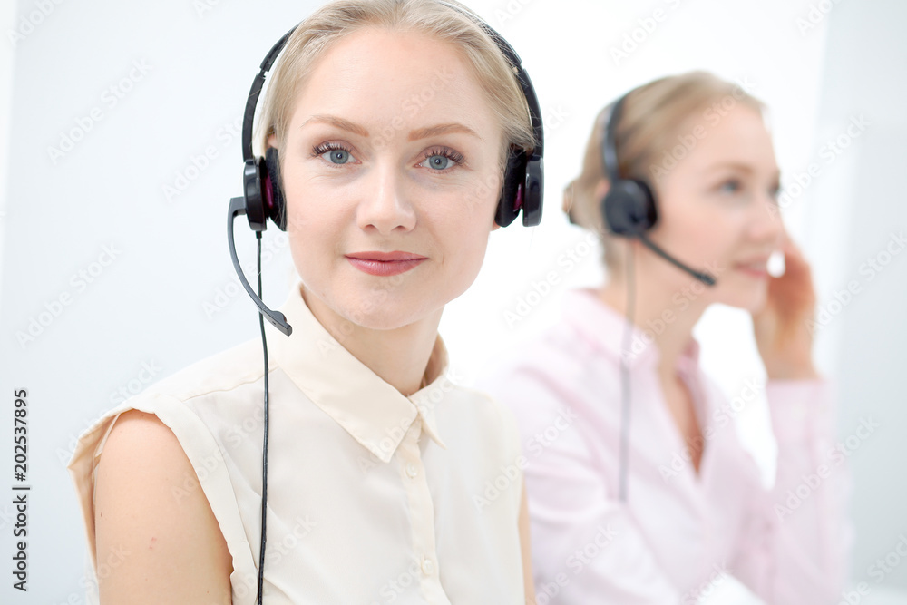 Image of bright call center. Focus on young beautiful woman in a headset Image of bright call center. Focus on young beautiful woman in a headset