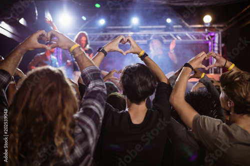 Crowd making heart shape with hands during performance