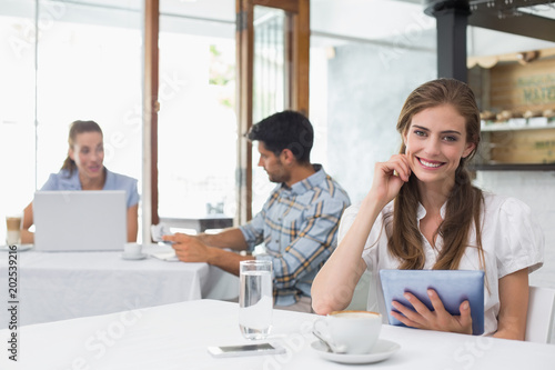 Smiling woman using digital tablet in coffee shop