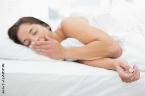 Blurred young woman yawning in bed