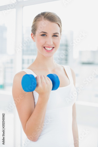 Cheerful fit woman exercising with dumbbells