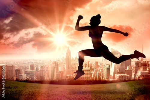 Fit brunette running and jumping against sun shining over city © vectorfusionart