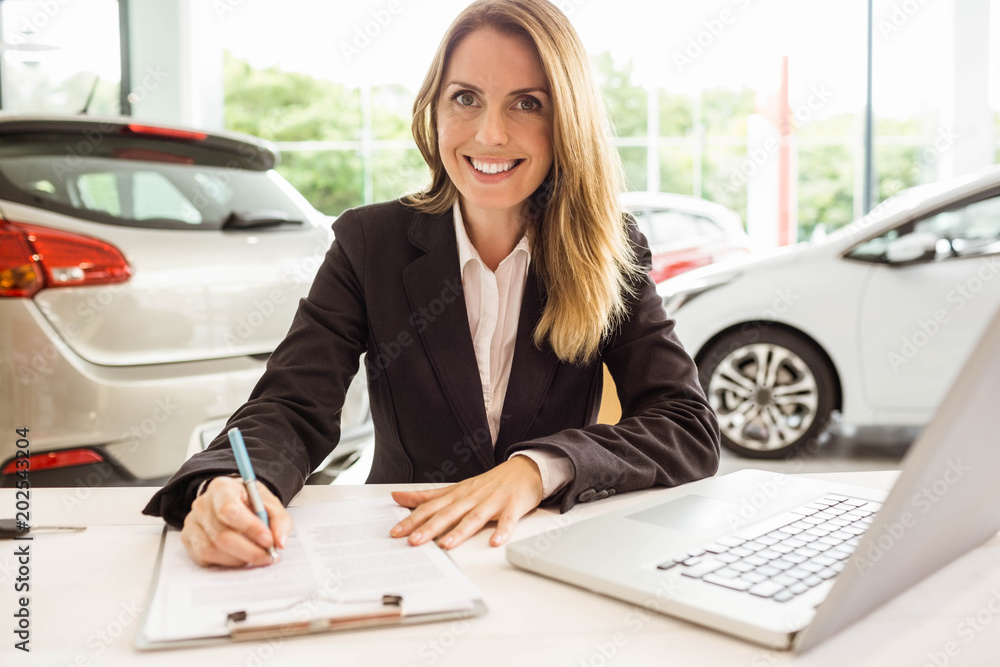 Smiling saleswoman writing on a clipboard Smiling saleswoman writing on a clipboard