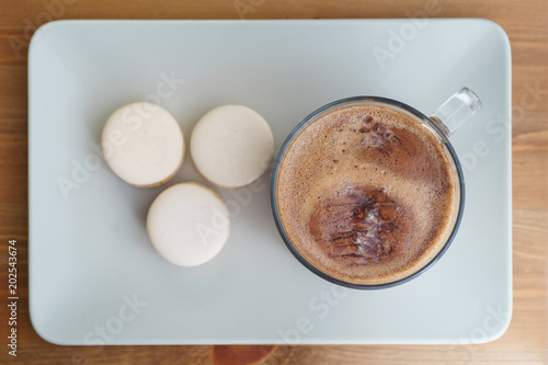 Delicious fresh traditional macaroon dessert cakes on a plate, on a wooden table with cacao and hot chocolate.