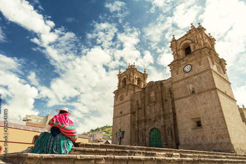 Woman with keperina (bag on her back) sitting on the steps of the Cathedral of Puno (Peru) photo