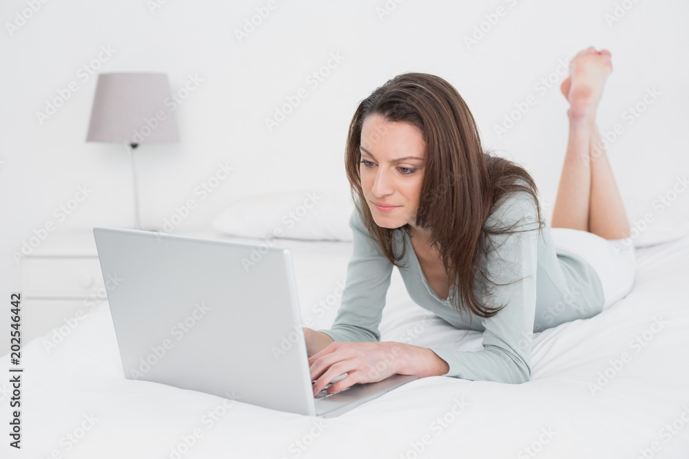 Relaxed casual woman using laptop in bed Relaxed casual woman using laptop in bed
