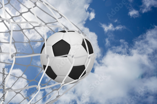 Football at back of net against bright blue sky with clouds © vectorfusionart
