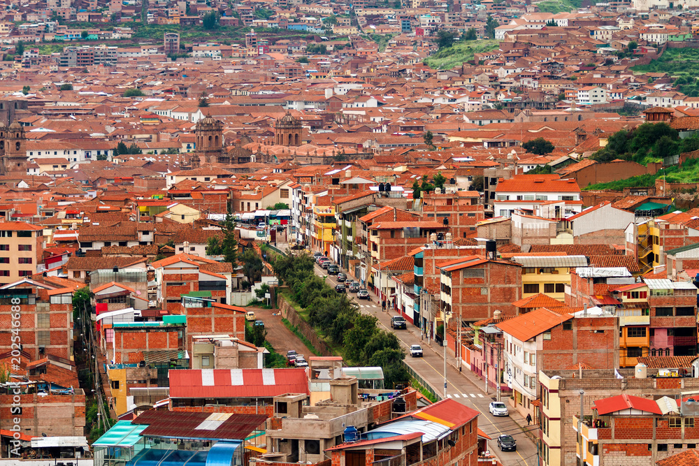 Aerial view of part of the city of Cusco (Peru) with buildings with roofs of tiles and mountains in the background