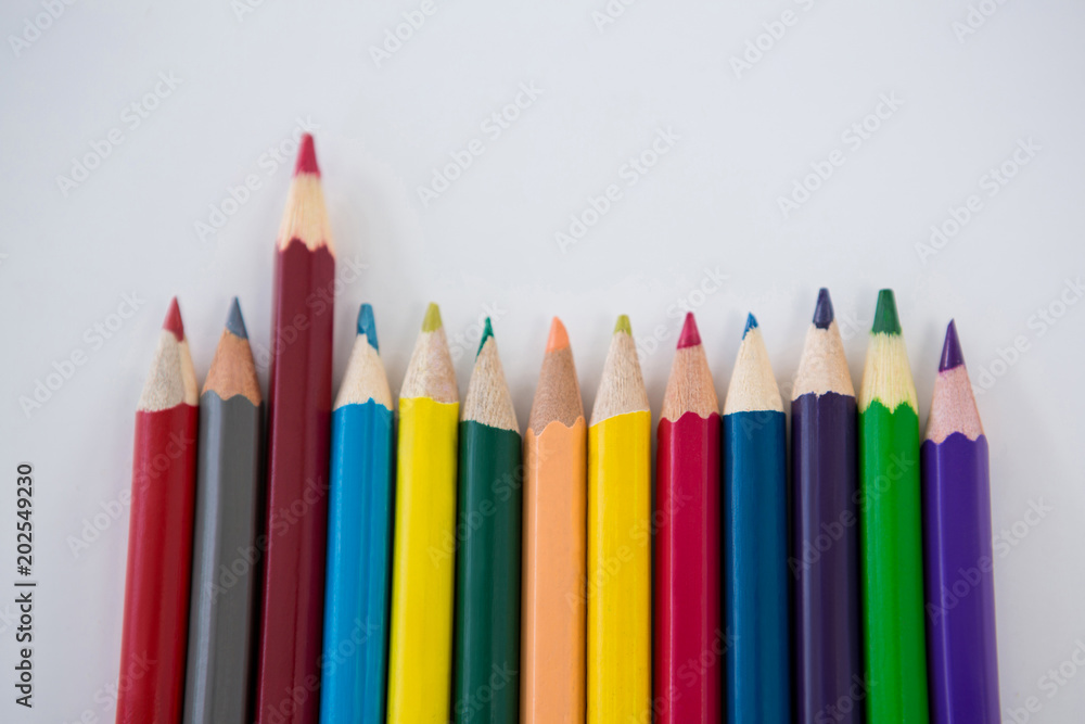 Colored pencils arranged in a row on white background Colored pencils arranged in a row on white background