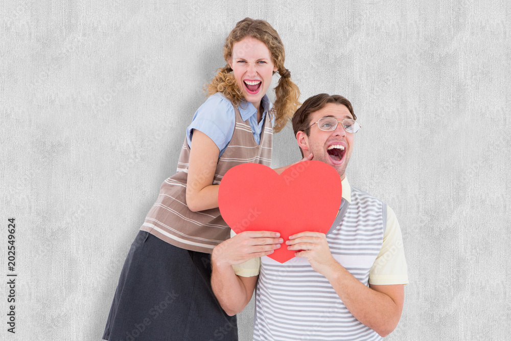 Excited geeky hipster couple with heart card against white background Excited geeky hipster couple with heart card against white background