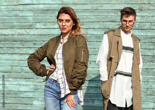 fashion couple in glasses with glasses in green clothes posing on blue wooden wall