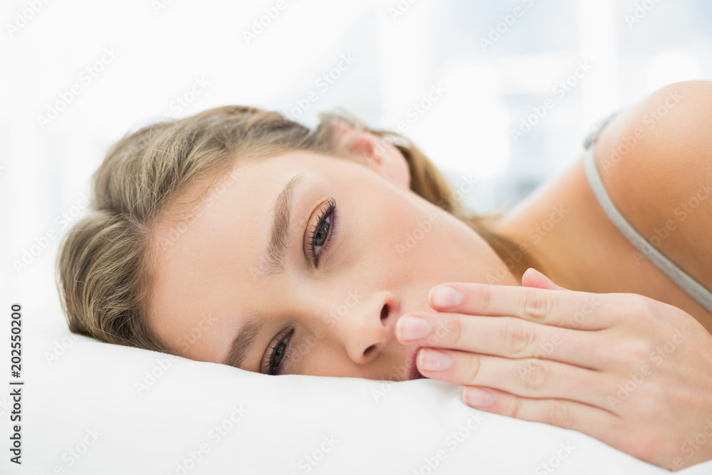 Obraz premium Peaceful tired woman lying in her bed yawning 