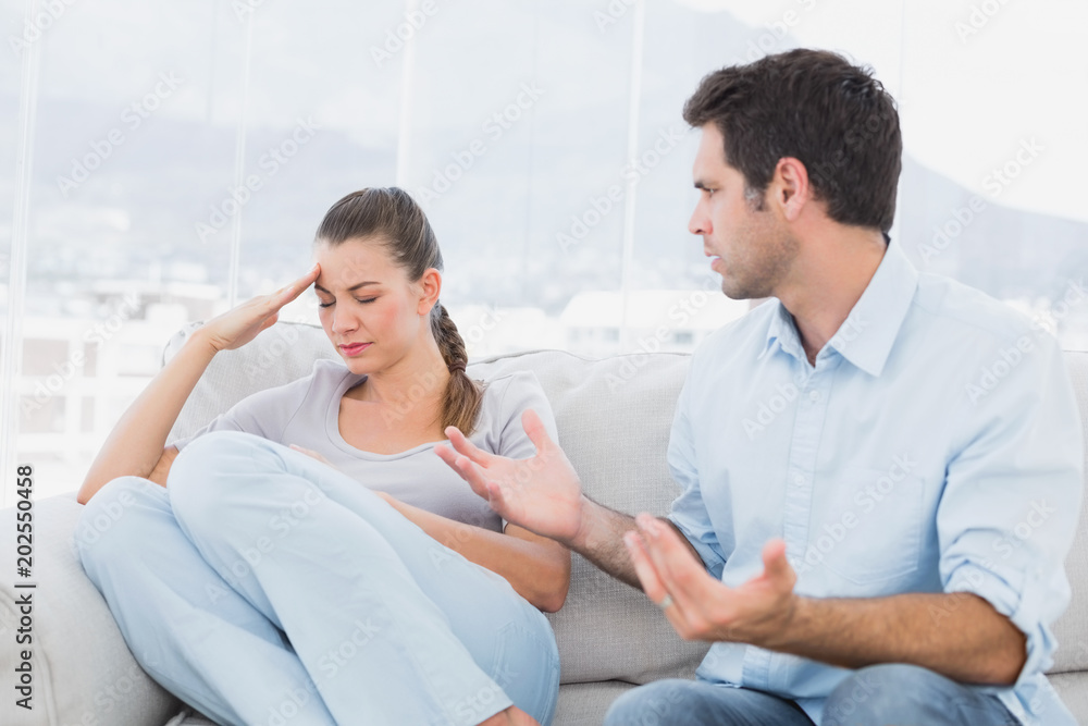 Man pleading with his upset partner on the couch Man pleading with his upset partner on the couch