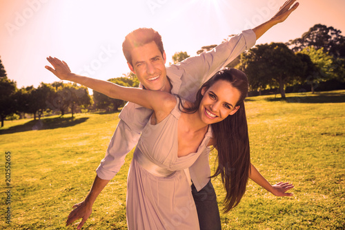 Portrait of a happy young couple with arms outstretched at the park