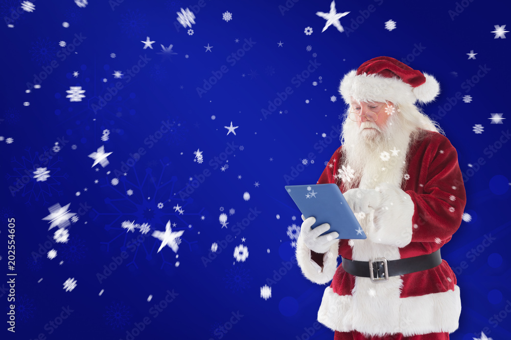Santa uses a tablet PC against blue snowflake background