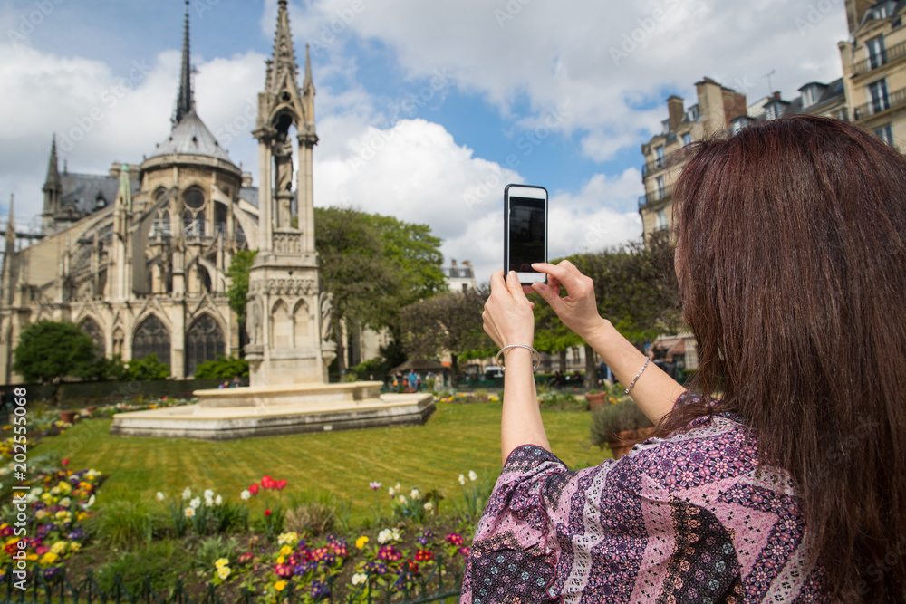 Φωτογραφία Woman taking photo with cell phone at Notre-Dame in Paris, France