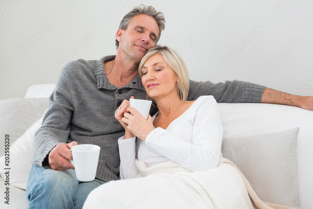 Relaxed couple with coffee cups in living room Relaxed couple with coffee cups in living room
