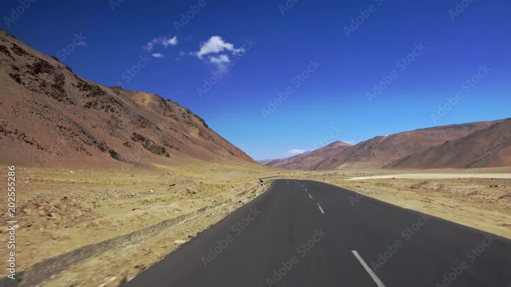 Camera moves along Leh-Manali Highway crossing More plains and flanked by Himalaya mountain range. View on amazing mountainous scenery from car driving along road on sunny day. Ladakh, India Camera moves along Leh-Manali Highway crossing More plains and flanked by Himalaya mountain range. View on amazing mountainous scenery from car driving along road on sunny day. Ladakh, India