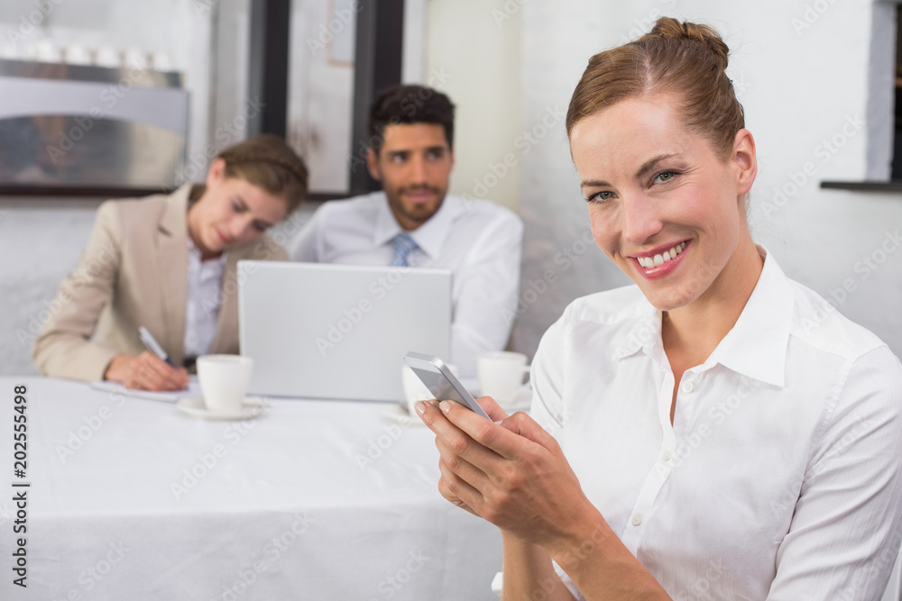 Businesswoman text messaging with colleagues at office desk Businesswoman text messaging with colleagues at office desk
