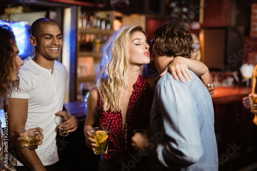 Friends looking at woman embracing man in club