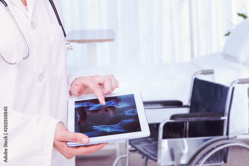 Doctor looking at xray on tablet against bright white room with windows Doctor looking at xray on tablet against bright white room with windows