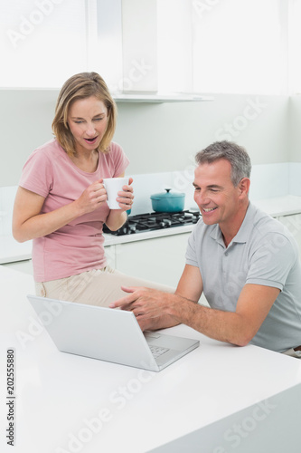 Couple using laptop while woman drinking coffee in kitchen © WavebreakmediaMicro