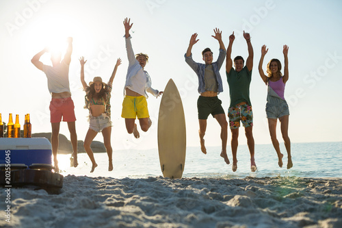Happy friends jumping on shore at beach