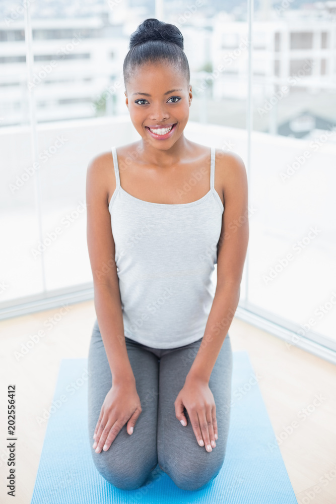 Happy woman sitting on blue exercise mat