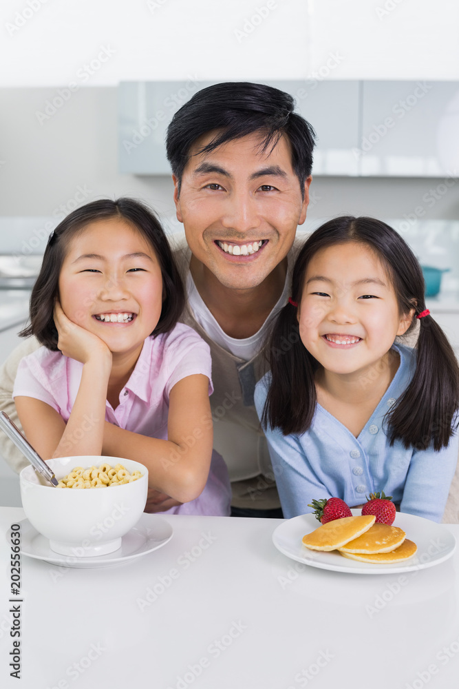 Smiling man with two daughters having breakfast in kitchen Smiling man with two daughters having breakfast in kitchen