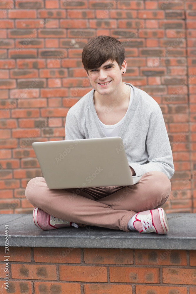 Man sitting on wall with laptop