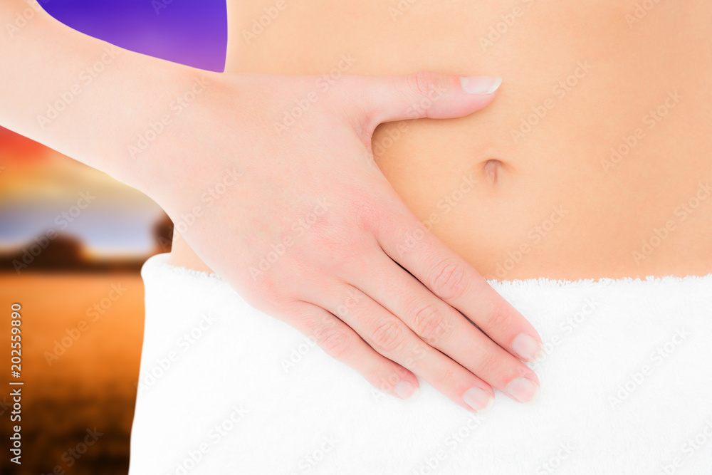 Mid section of a fit woman with hand on stomach against countryside scene Mid section of a fit woman with hand on stomach against countryside scene
