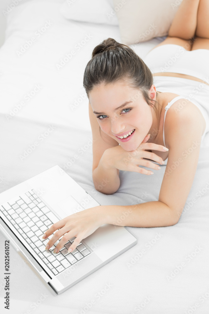 Smiling casual woman using laptop in bed Smiling casual woman using laptop in bed