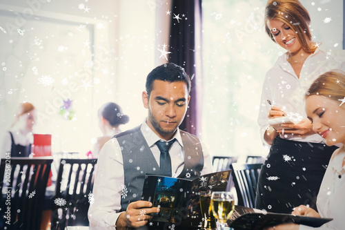 Composite image of two business people ordering dinner against snow falling