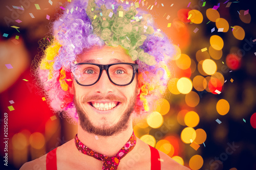 Geeky hipster in afro rainbow wig against desk with christmas tree in background