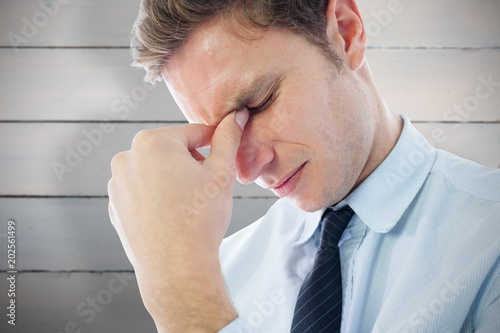 Businessman with a headache against painted blue wooden planks