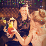 Female friends toasting glasses of cocktail against flying colours