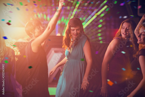 Group of smiling friends dancing on dance floor against flying colours