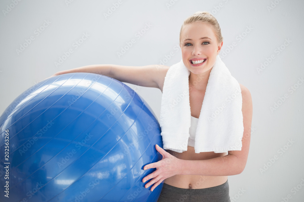 Cheerful sporty blonde with towel around her neck holding exercise ball Cheerful sporty blonde with towel around her neck holding exercise ball