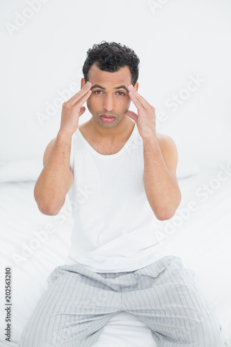 Young man suffering from headache in bed