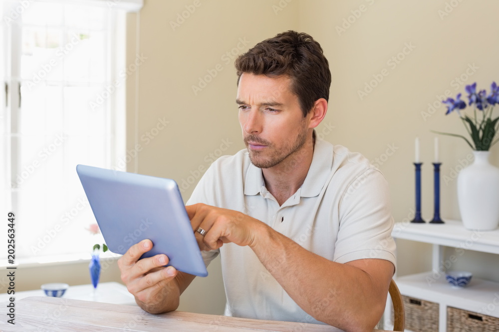 Concentrated man using digital tablet on table